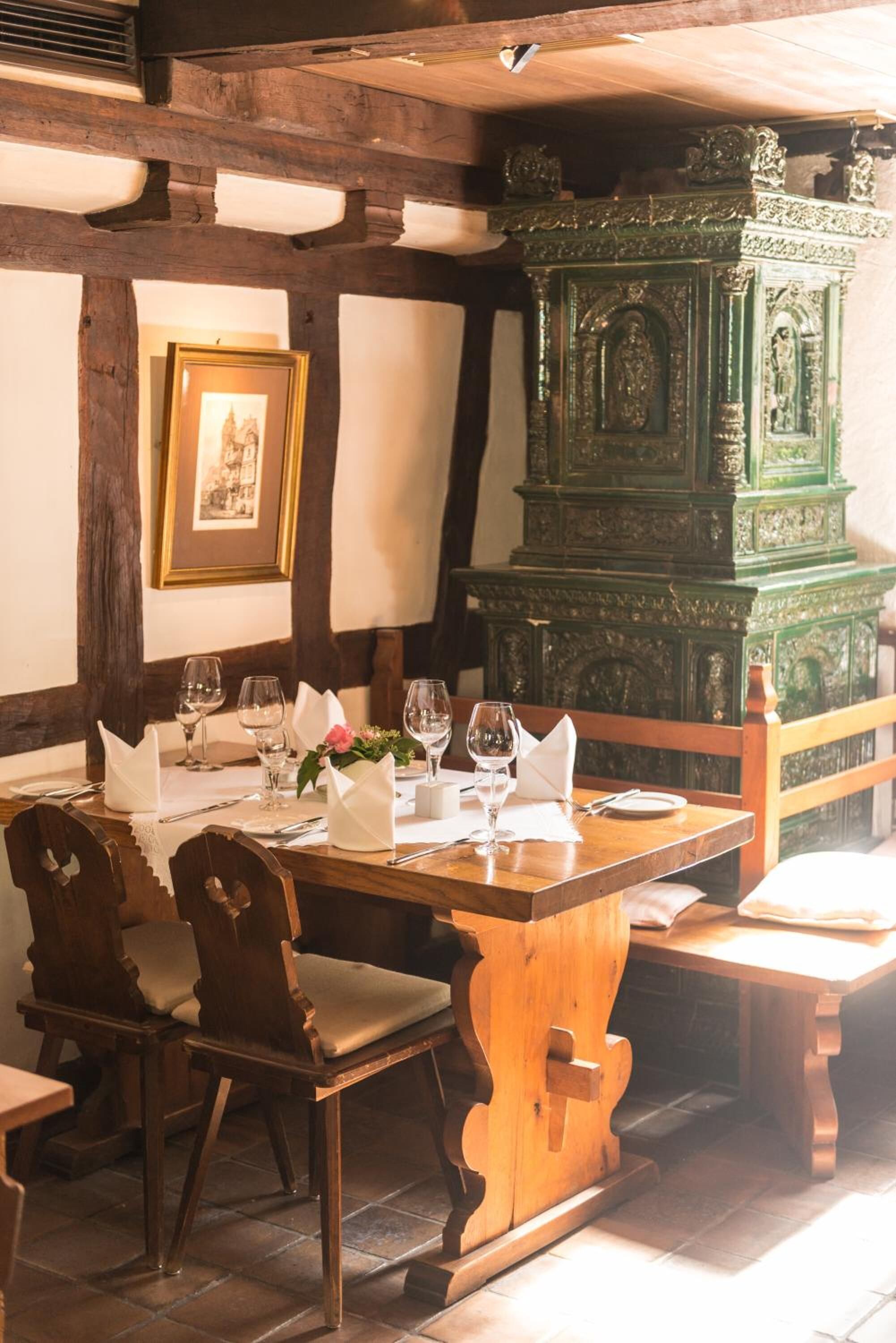 A dining table set with chairs, a green ornate cabinet, and a framed picture on the wall.
