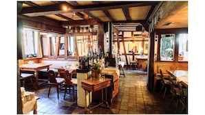 A rustic interior with wooden beams, a bar area with bottles, and a dining space with tables and chairs. - Hotel Landgasthof Zum Weissen Schwanen (Braubach)