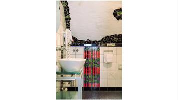 A bathroom with a white sink, a mirror, and a tiled wall with a colorful pattern.