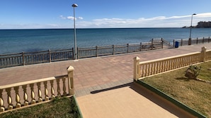 Un paseo marítimo con una pasarela de madera, barandas de metal y un farol.