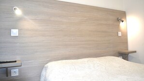 Een slaapkamer met een houten hoofdbord, nachtkastjes en een bed met een witte dekbedovertrek.