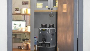 Een kleine kitchenette met een koffieapparaat, een fles wijn en een kleine koelkast.