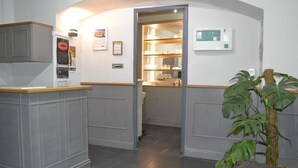 Een receptie met een balie, een plant en een deur naar een keuken.