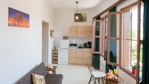 A compact living space with a sofa, dining table, chairs, and a kitchen area. - Emerald Dream House (Rhodes)