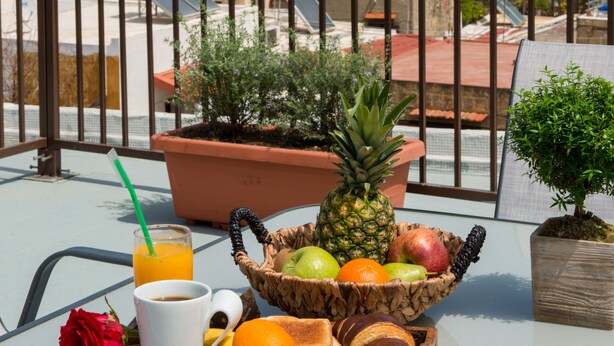 A balcony with a breakfast tray, a rose, a pineapple, and a view of the cityscape including a mosque. - Emerald Dream House (Rhodes)