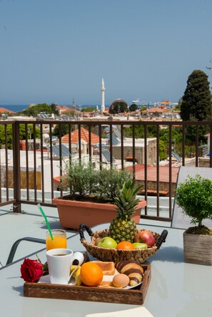 Een balkon met een ontbijttafel, een roos, een ananas en een uitzicht over de stadsgezicht, inclusief een moskee.