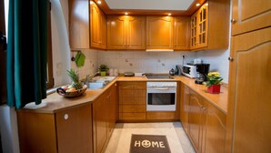 A compact kitchen with wooden cabinets, a built-in oven, and a microwave. - Emerald Dream House (Rhodes)