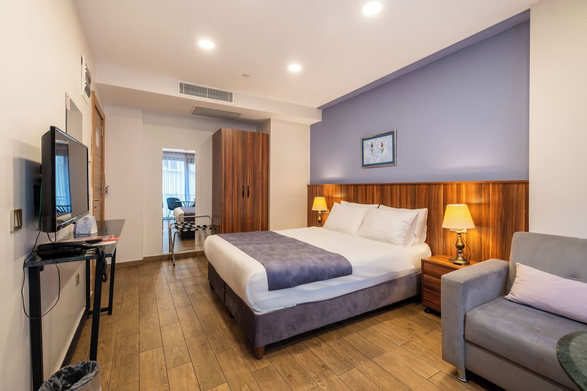 A hotel room with a large bed, a desk with a computer, a chair, and a TV.