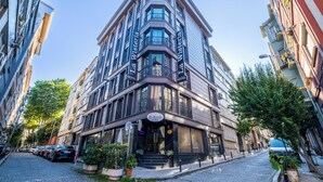 Un edificio en esquina con letrero que dice "La Wisteria", de diseño moderno con ventanas grandes y balcones.