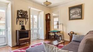 A living room with a sofa, a television, a billiards table, and a clock. - JOIVY Lovely 3BR Apt w/ workspace, nearby Botanical Garden of Lisbon (Lisboa)