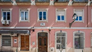 A pink building with three windows, a wooden door, and a street lamp. - JOIVY Lovely 3BR Apt w/ workspace, nearby Botanical Garden of Lisbon (Lisboa)