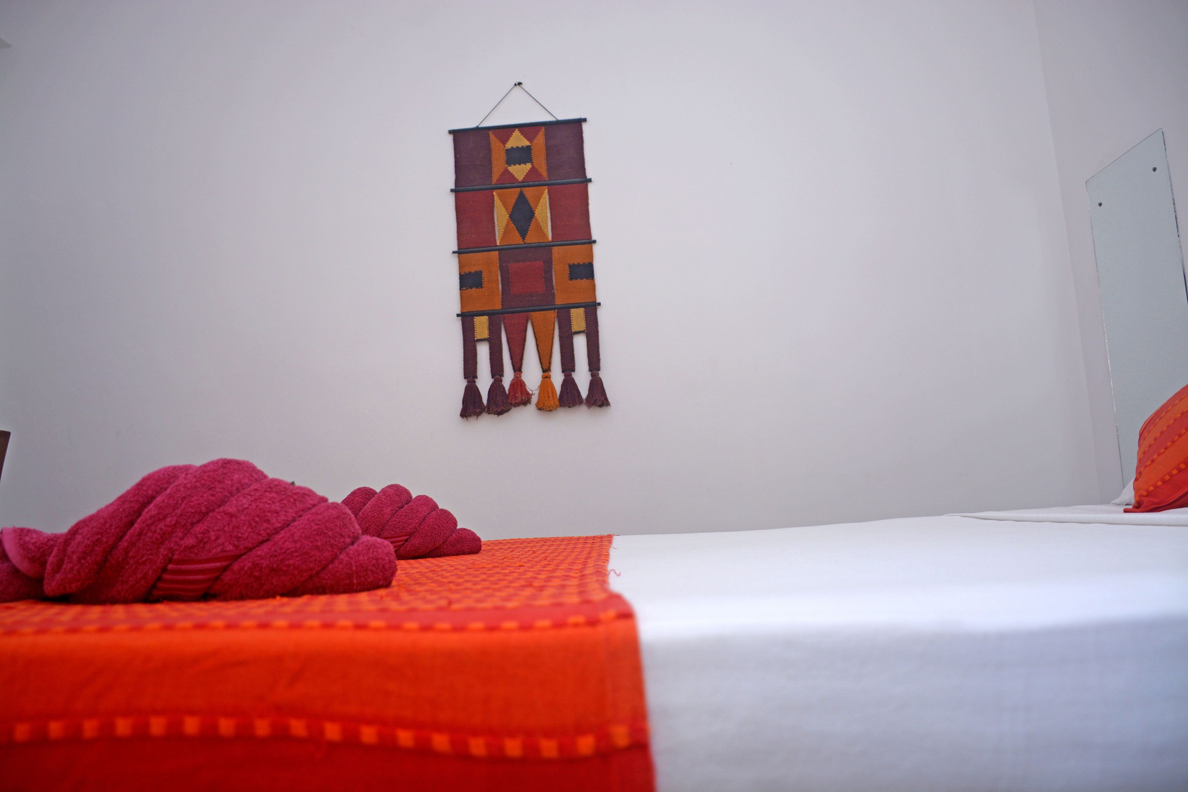 Un dormitorio con una cama, un tapiz colgante y una manta roja.
