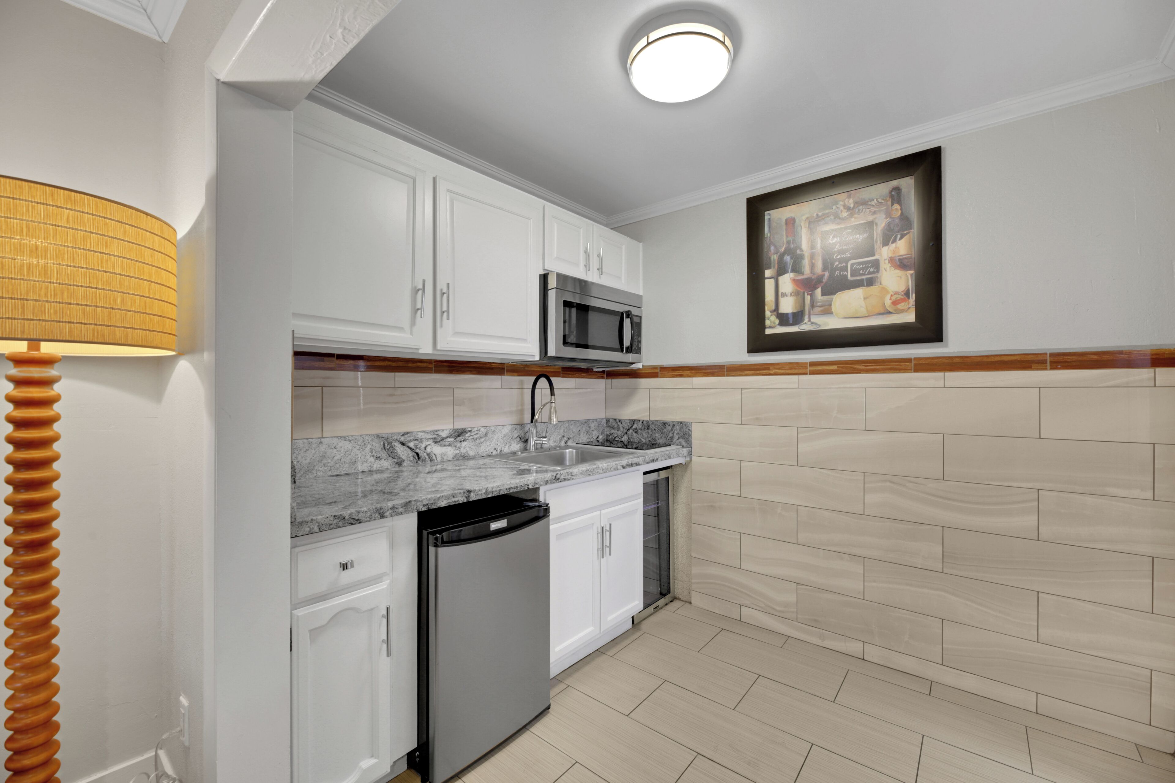 A kitchen with white cabinets, a built-in microwave, a dishwasher, and a tiled backsplash.