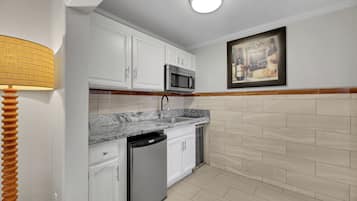 A kitchen with white cabinets, a built-in microwave, a dishwasher, and a tiled backsplash.