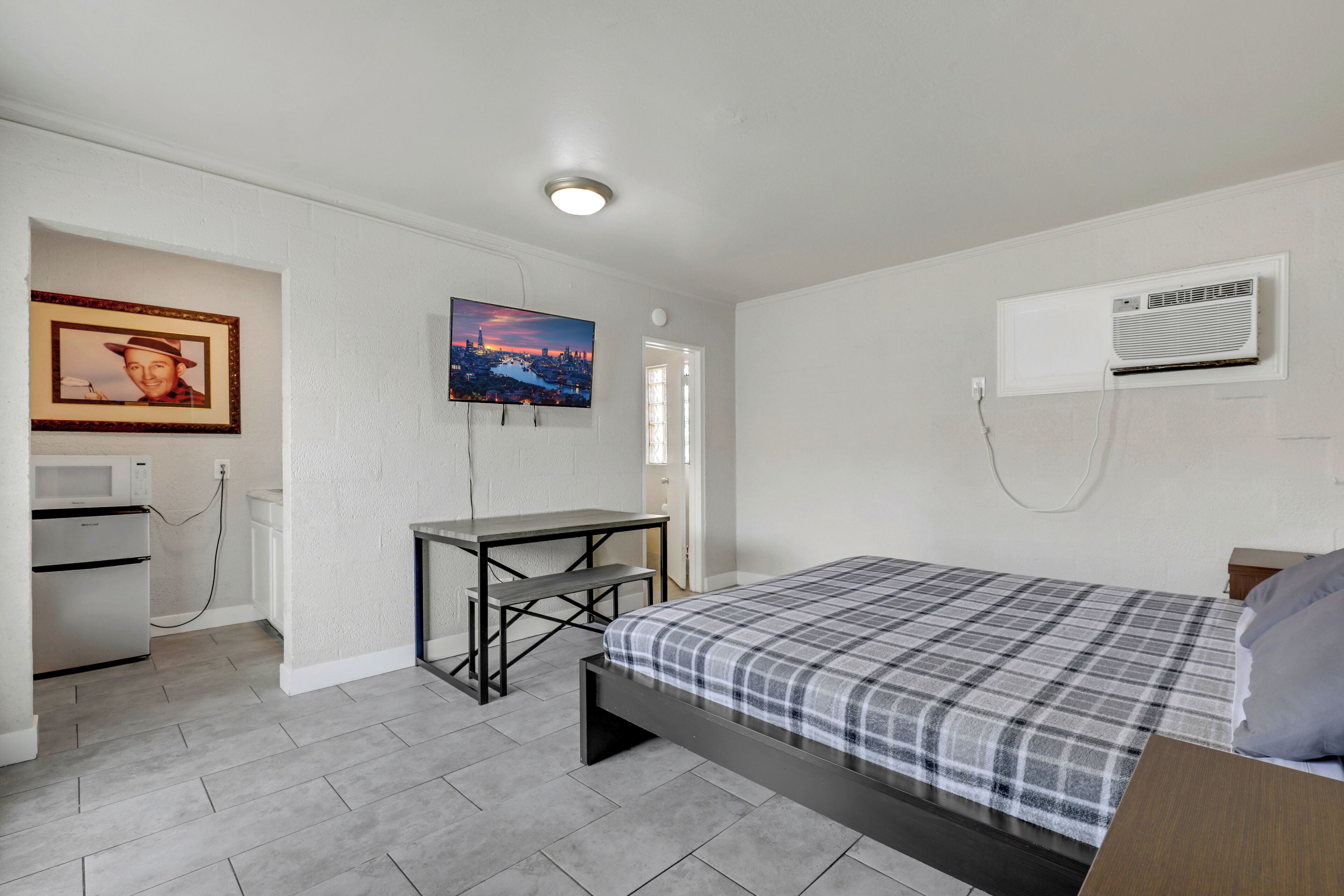 Una camera da letto con un letto, una scrivania, un forno a microonde e un condizionatore.