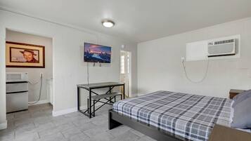 Una camera da letto con un letto, una scrivania, un forno a microonde e un condizionatore.
