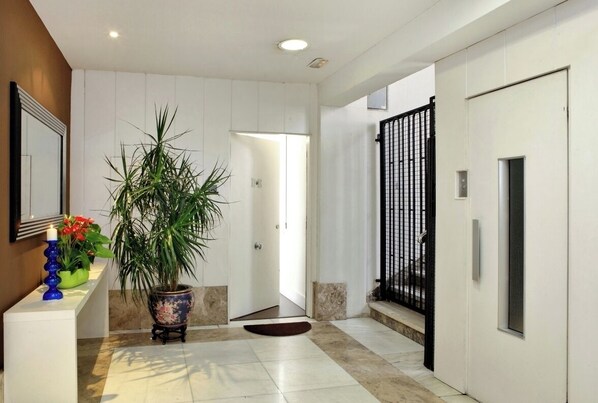 Welcome to our lobby, featuring a reception desk, a potted plant, and a large plant in the center.