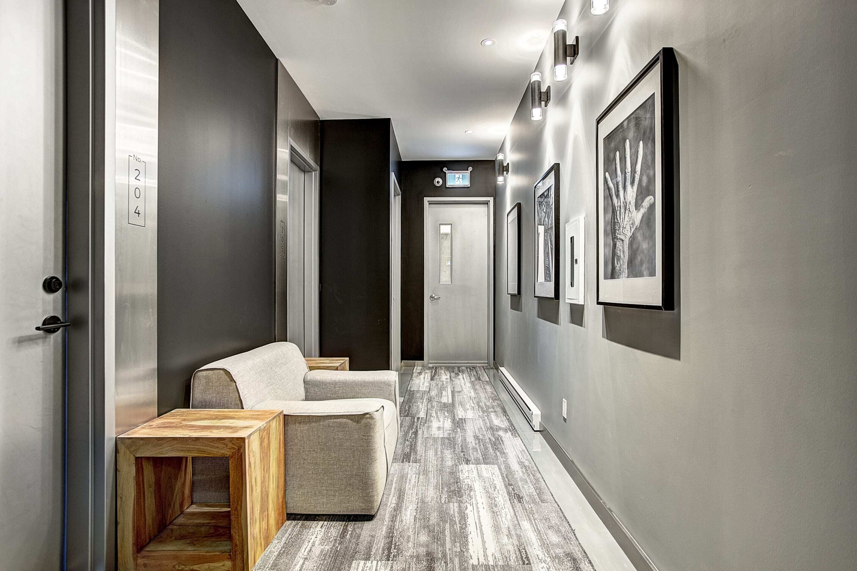 A hallway with a sofa, a wooden side table, and framed artwork on the walls.