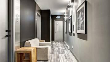 A hallway with a sofa, a wooden side table, and framed artwork on the walls.