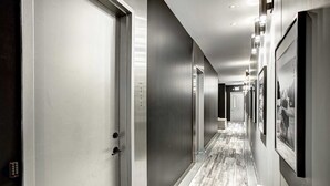 A modern hotel hallway with metallic doors, a wooden floor, and framed pictures on the walls. - Les Lofts du Centre (Montreal)
