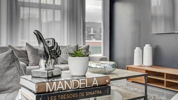 Ein modernes Wohnzimmer mit einem Glastisch, einer Büchersammlung, einer dekorativen Skulptur und einem Topfpflanzen.