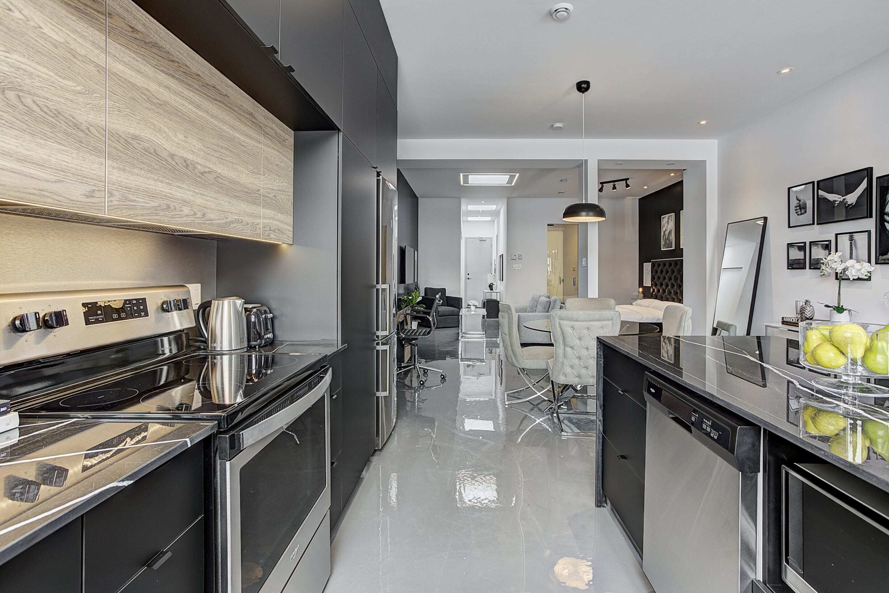 Une cuisine moderne dotée d’appareils électroménagers en acier inoxydable, d’un îlot central et d’un coin repas avec une table et des chaises blanches.