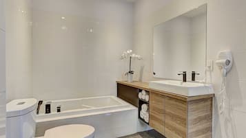 A modern bathroom with a bathtub, toilet, vanity with a mirror, and a towel rack.