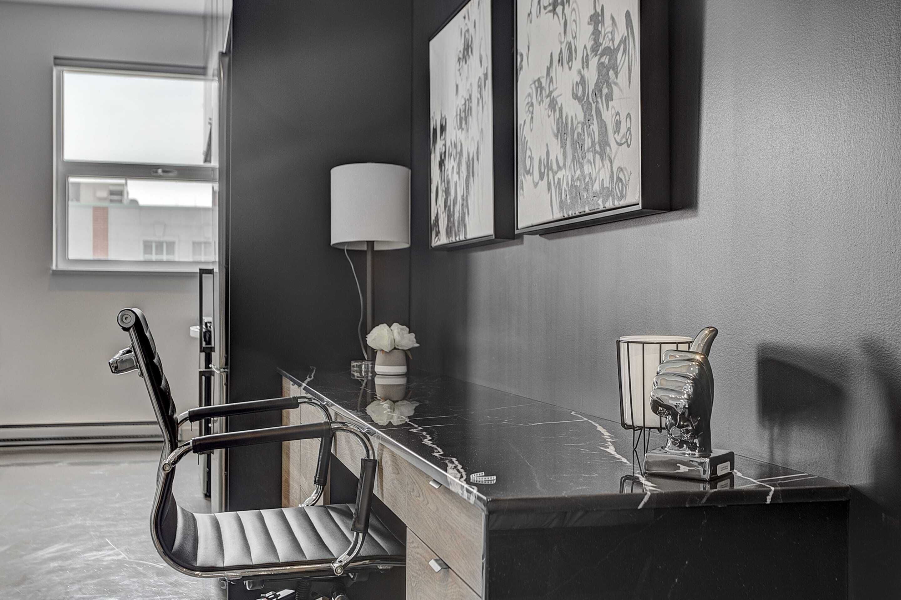 A modern office space with a desk, chair, and artwork on the wall.