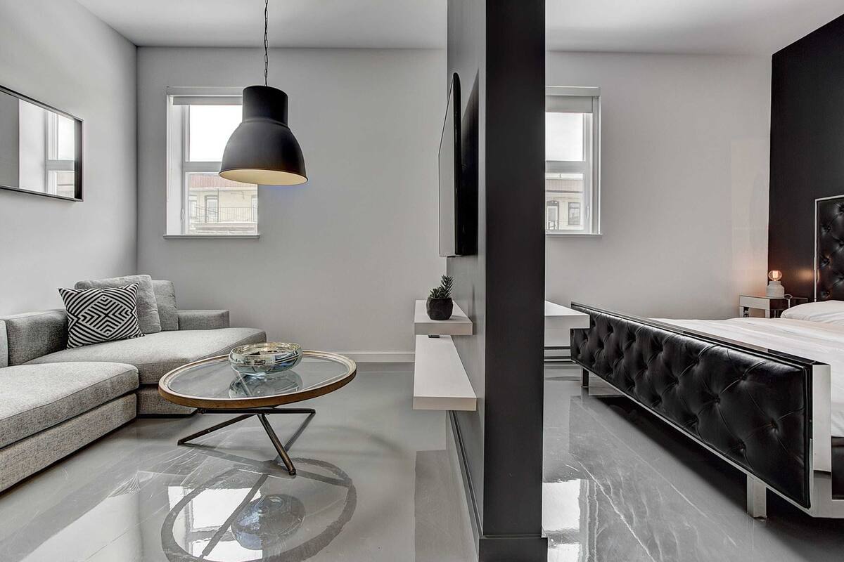 A modern bedroom with a bed, bedside tables, a sofa, and a round coffee table.