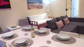 A dining area with a table set for four, a sofa, and a bed in the background.