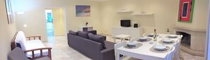 A living room with a sofa, a dining table set for four, a TV, and a fireplace.