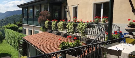 Une terrasse dotée d’un toit en tuiles, de sièges extérieurs et de plantes en pot.