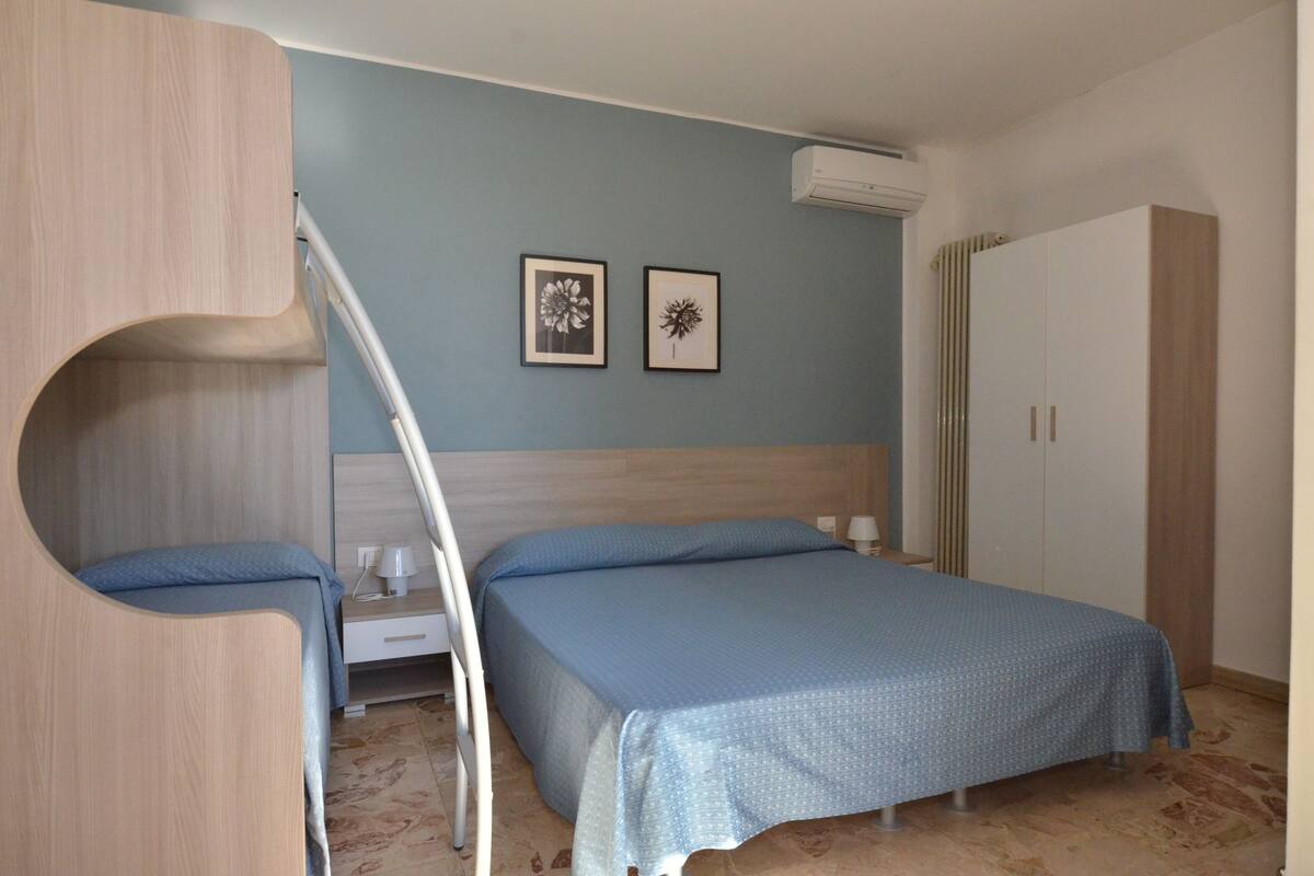 A bedroom with a bed, a wardrobe, and two framed pictures on the wall.