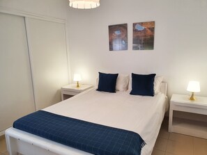 A bedroom with a bed, two bedside tables, and two wall-mounted lamps. - Praiamar 3f- Sea Front, Cozy, Private Parking (Quarteira)