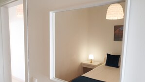 Une chambre à coucher comprenant un lit, une table de chevet, une lampe et un luminaire fixé au mur.