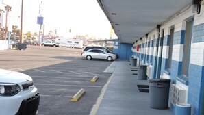 A parking area with a row of trash bins and a building with blue and white walls. - Walden Motel (Las Vegas)
