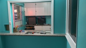 A small kitchenette with a window, a sink, and a countertop with various items. - Walden Motel (Las Vegas)