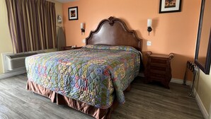 A hotel room with a large bed, a wooden nightstand, a wall-mounted lamp, and a framed picture on the wall. - Walden Motel (Las Vegas)