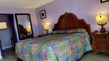 Quarto com uma cama grande, duas luminárias de cabeceira, cômoda de madeira e um espelho.