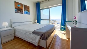 Una camera da letto con un letto, un comodino, una cassettiera e vista sul balcone.