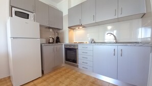 Una cucina moderna con mobili grigi, forno integrato, microonde e lavello.