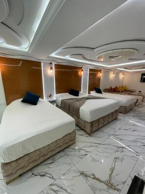 A modern hotel room with three beds, marble flooring, and contemporary lighting fixtures. - Puerto Marino (Al Hoceima)
