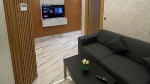 Una sala de estar moderna con un sofá seccional, una mesa de centro y un televisor montado en una pared de paneles de madera.