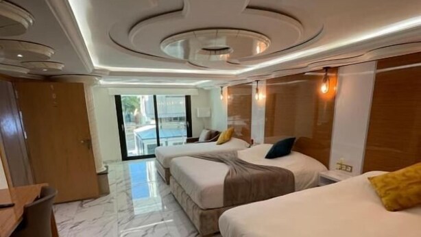 Habitación de hotel con piso de mármol, dos camas, un escritorio y vistas al exterior.