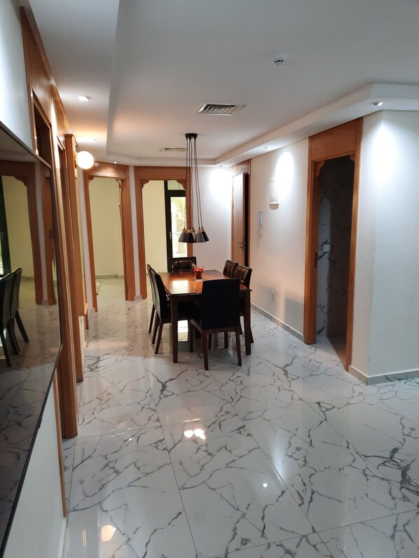 A spacious dining area with a marble floor, wooden furniture, and pendant lighting. - Puerto Marino (Al Hoceima)
