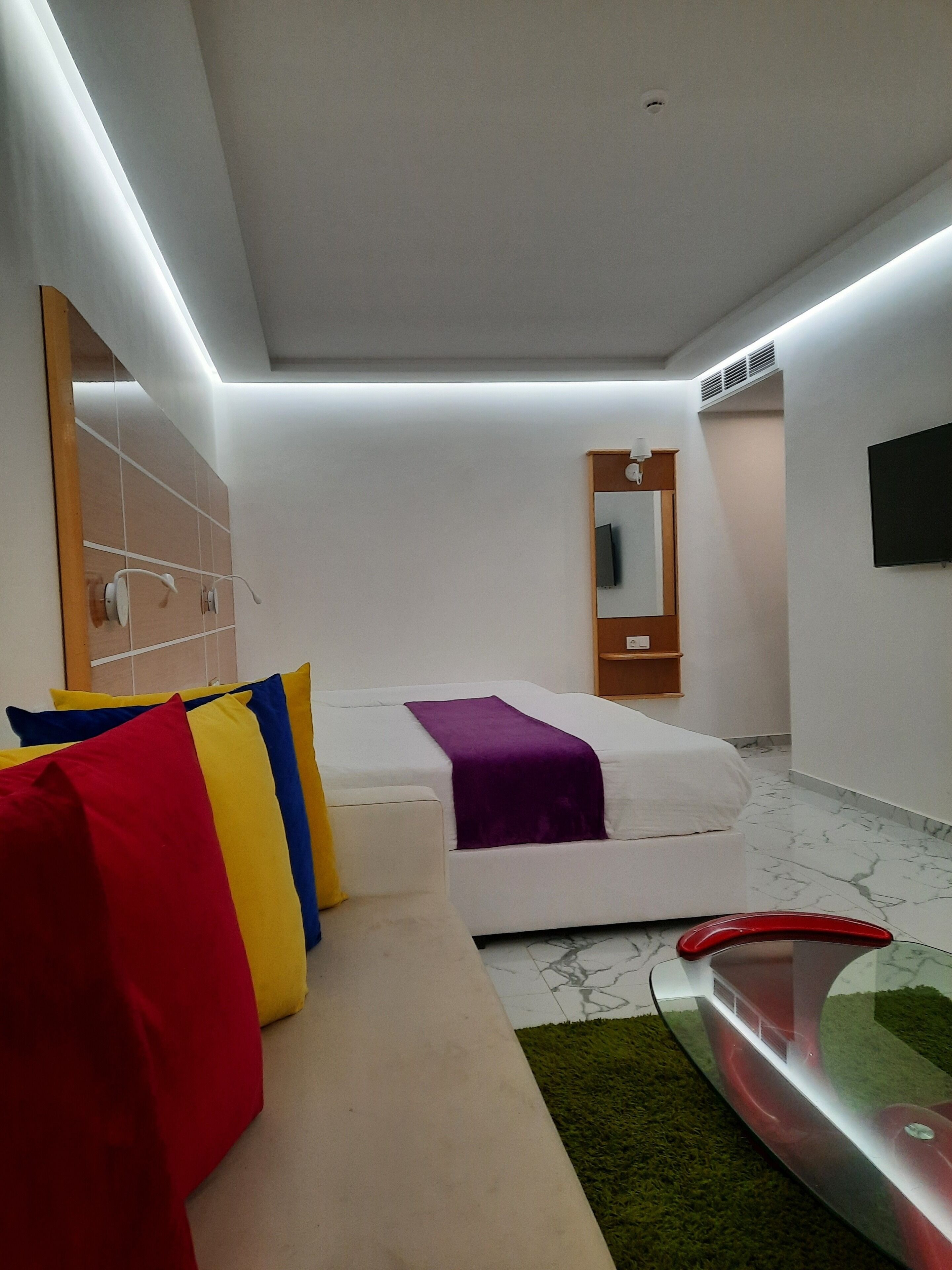 Una habitación de hotel moderna con una cama, un sofá, un televisor y un baño.