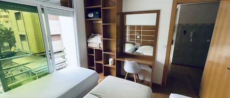 A hotel room with a bed, a desk with a chair, a wardrobe, and a bathroom.