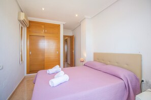 A bedroom with a bed, a wooden wardrobe, a bedside table, and a lamp. - Listen to the sound of the med with this brand new fronline property! (La Manga del Mar Menor)