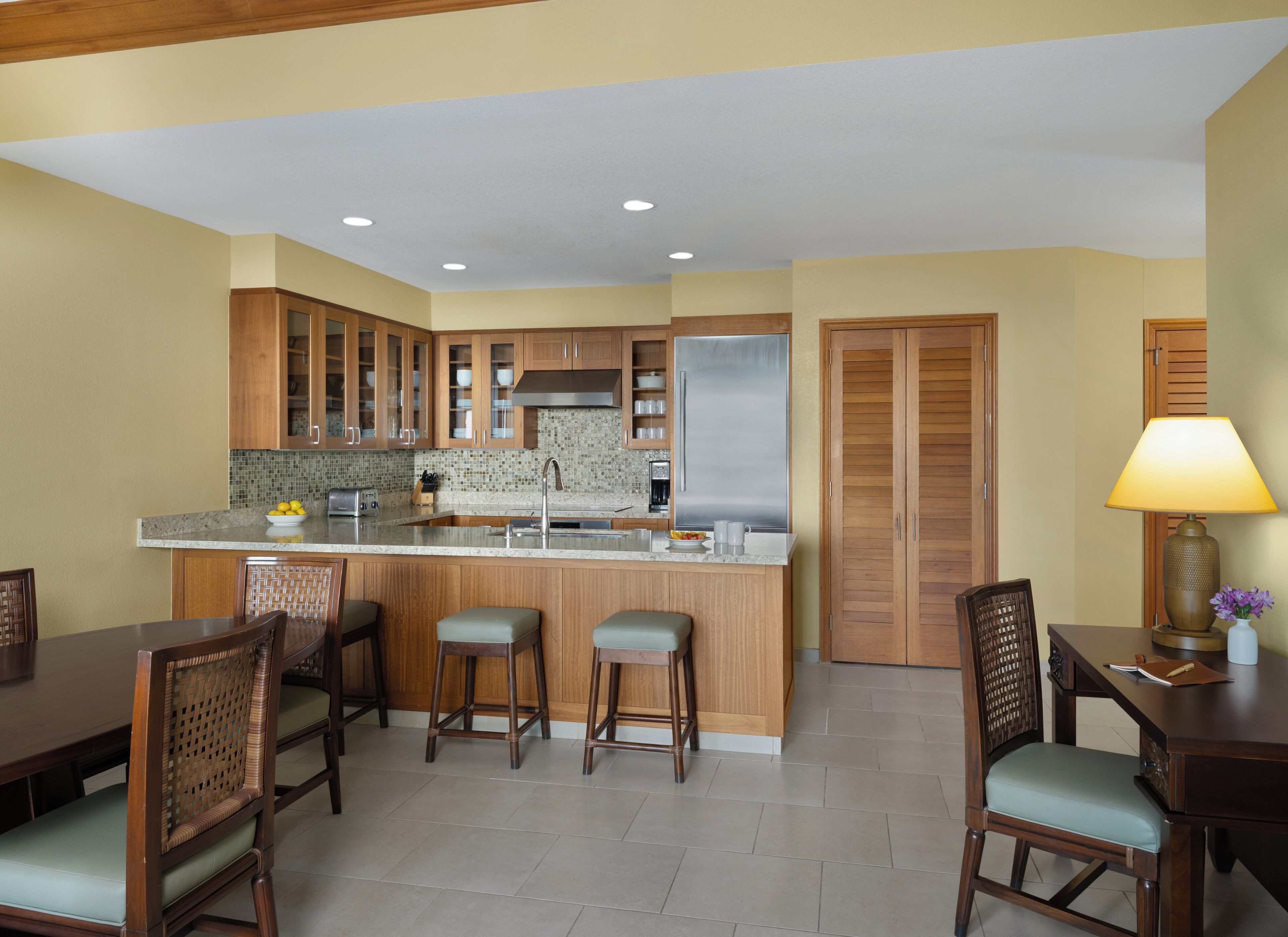A modern kitchen with wooden cabinets, a central island, and a dining area with bar stools.