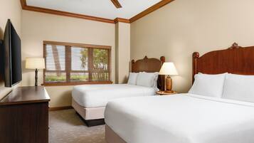 A hotel room with two beds, a ceiling fan, a TV, and a window with blinds.
